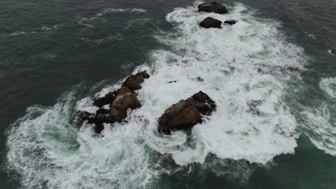 Aerial Orbit of Large Ocean Rocks with Crashing Waves and White Foam in Fog Stock Footage 323314546