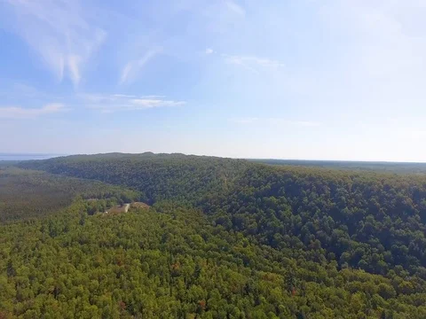 Aerial orbit left over rolling hills and densely wooded landscape Stock Footage 80896151