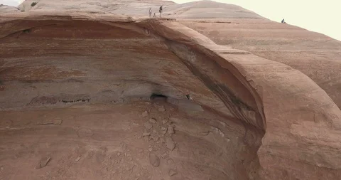 Aerial orbit of man rappelling/abseiling through a huge sandstone arch Stock Footage 111406773