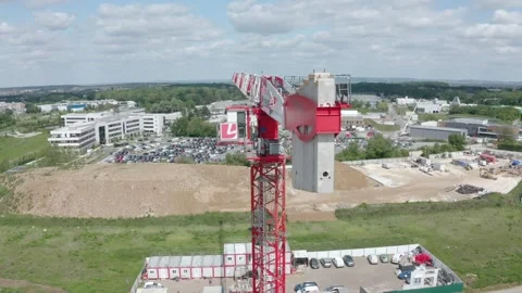 Aerial orbit shot around a tower crane above a construction site, with a modern Stock Footage 336286835