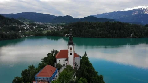 Aerial orbit shot of charming tiny island with medieval church and mountains Vídeo Stock 195970333