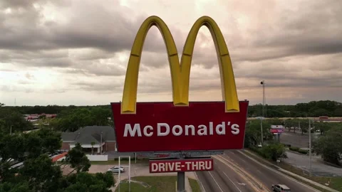 Aerial orbit shot of Mc Donald´s Sign against sunset cloudy sky in American Stock Footage 312192953