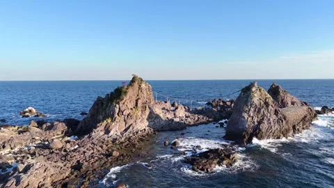 Aerial Orbit Shot of Mitsuishi Rocks with Shimenawa Rope at Manazuru Cape Stock Footage 329058009