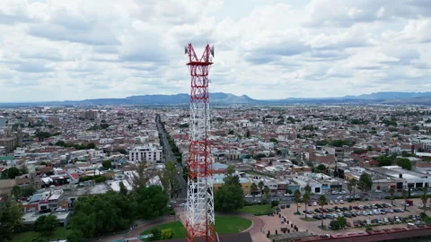 Aerial orbit of a telecom tower and city rooftops Stock Footage 342062730