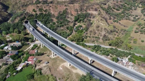 Aerial orbit view of highway overpass and tunnels in mountain valley Stock Footage 343962871