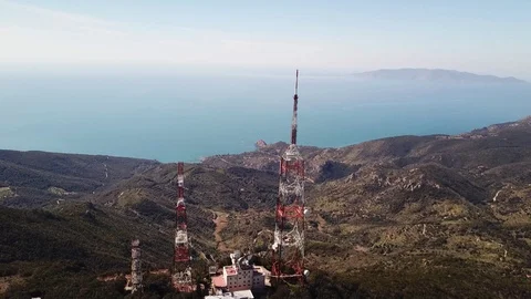 Aerial orbital view, trellis structures on a peak with the seacoast at  distance Stock Footage 105240846