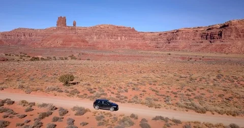 Aerial: orbiting black car as it drives desert road through Valley of the Gods Video stock 101863481