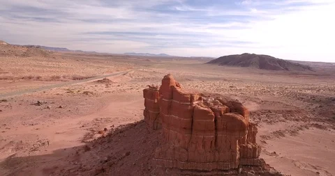 Aerial orbiting massive rock formation in red desert landscape Stock Footage 100077433