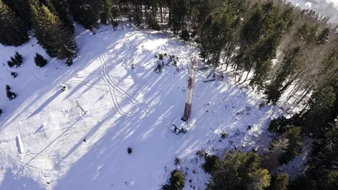 Aerial orbiting shot of a telecommunication tower on a snowy mountain peak in Stock Footage 336384297