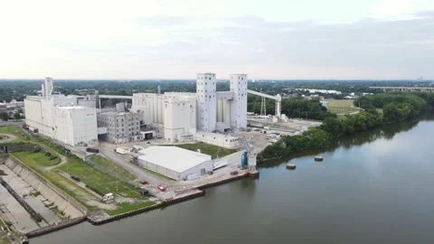 Aerial orbiting view of a large grain elevator facility along a river on a Stock Footage 235814426