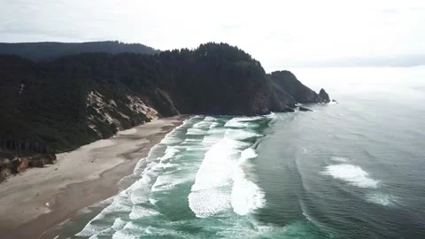 Aerial of Oregon's large sandy beaches with towering rocks in the distance Stock Footage