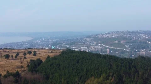 Aerial Over Dense Forest High Above Swansea City with Hazy Cityscape Below Stock-Footage 333385605