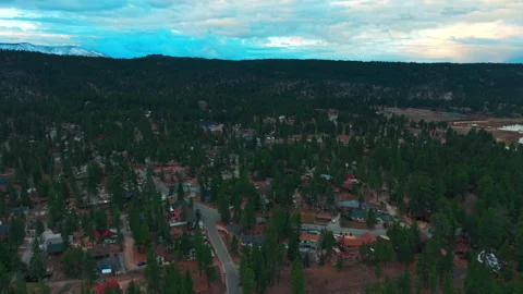 Aerial over dense forest surrounding Big Bear Lake with rolling green hills 库存影片 328898617