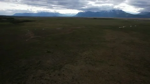 Aerial Over Flat Plain Tilt Up To Reveal Mountains Under Dramatic Cloudy Sky Stock Footage 170165719