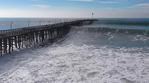 Aerial over huge waves rolling in over a California pier in Ventura California Stock Footage 102506000