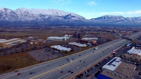 Aerial Over Interstate Traffic at Sunset with Snow Covered Mountains Vídeos de archivo 77112682