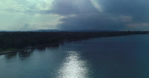 Aerial Over Last Sun Rays On Lake As It Disappears Behind A Storm Cloud Horizon Stock Footage 188031738