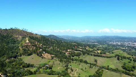 Aerial over mountain range covered with dense green forest and village in the Stock Footage 202294696