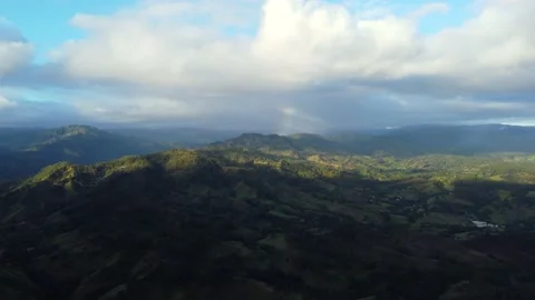 Aerial over mountain range covered with dense green forest and valley near Stock Footage 202298763