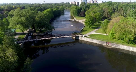 Aerial Over Nice River Pond Park And Pedestrian Bridge Landscape In Small Town Stock Footage 200817185
