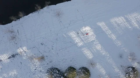 Aerial over people pulling a sled next to a lake with snow Stock Footage 111663258