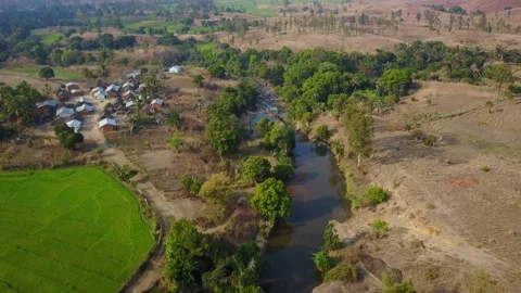 Aerial over rice fields, trees, village and Amboaboa River Madagascar Stock Footage 230232763