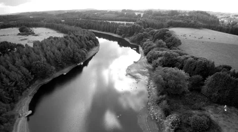 Aerial over a river flowing through hills in countryside. Black and white. 4K Stock Footage 68522797
