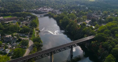 Aerial Over River Train Trestle And Dam Waterfalls Through Nice Town In Valley Stock Footage 200828222