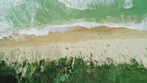 Aerial over the sandy beach with azure water and waves crashing to the shore on Stock Footage 219774527