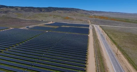 Aerial over solar panel field with golden poppy wildflower covered mountains Stock Footage 104812612