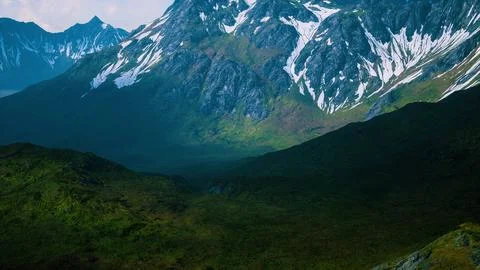 Aerial Over Valley With Snow Capped Mountains In Distance Ilustração Stock
