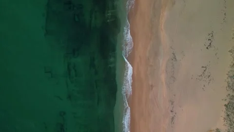 Aerial overhead drone view of waves gently breaking on sandy beach shore Stock Footage 293064097