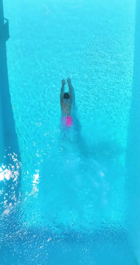 Aerial overhead slow motion view of a man diving into a swimming pool Stock Footage 278030840