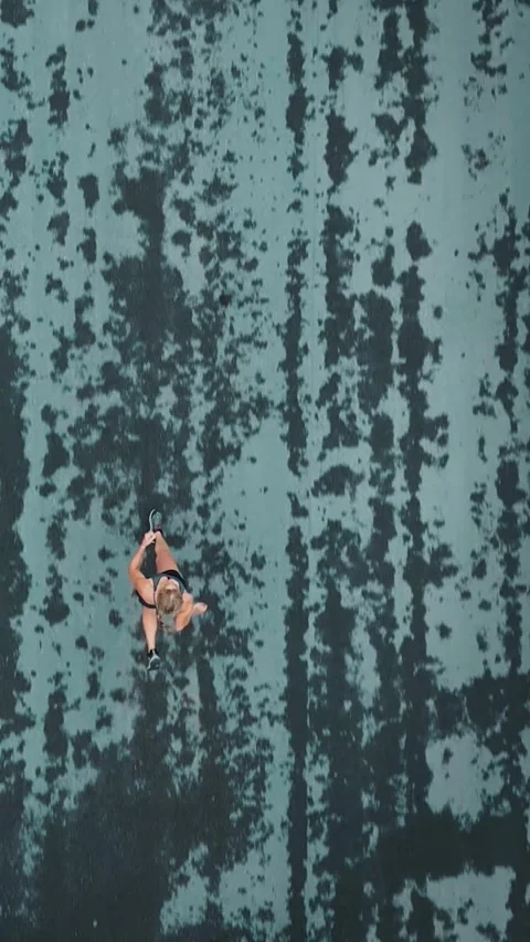 Aerial overhead view of female runner on a textured wet road Stock Footage 340047015
