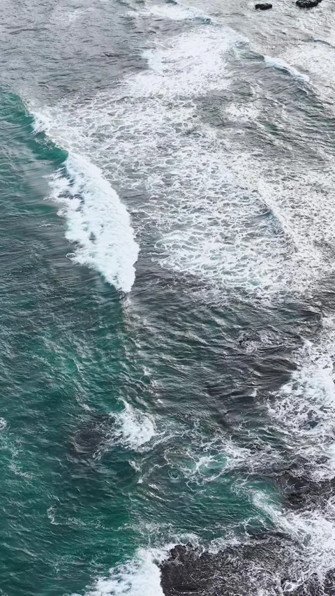 Aerial Overhead View of Ocean Waves Breaking Over Rocky Shore Stock Footage 345100409