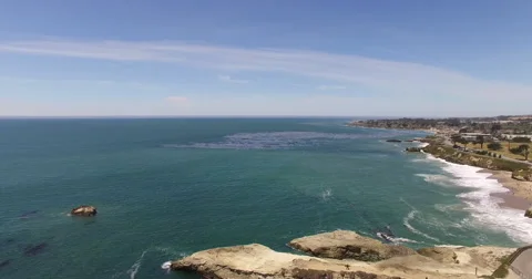 Aerial pan down over surfers and the Surfer Museum in Santa Cruz, 4K Stock Footage 64681430