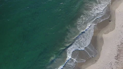 Aerial Pan down of waves rolling onto the beach in summer Stock Footage 157235146