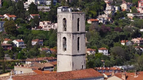 Aerial pan of Grasse bell tower and clock tower over terracotta roofs Stock Footage 333377410