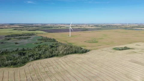 Aerial pan of harvested fields, forest, and a distant wind farm. Stock Footage 316638108