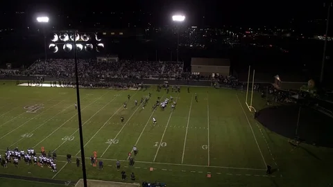 Aerial pan of high school football game at night Stock Footage