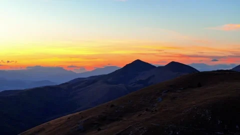 Aerial Pan Left Across Mountain Silhouettes at Sunset Near Rocca Calascio Italy Stock Footage 346472621