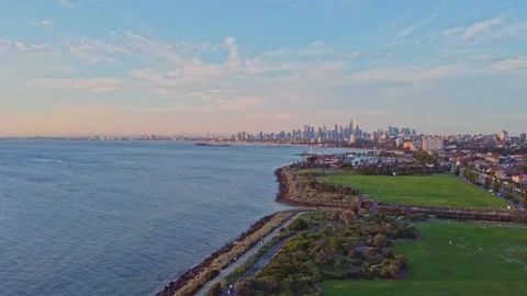 Aerial pan of Melbourne CBD skyline over coastline at sunset Stock Footage 321783337