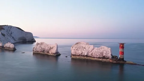 Aerial Pan of the Needles Lighthouse and Cliffs at Dawn with Golden Sky Stock Footage 338065607