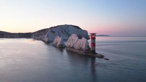 Aerial Pan of the Needles Lighthouse and Cliffs at Dawn with Golden Sky Stock Footage 338065663