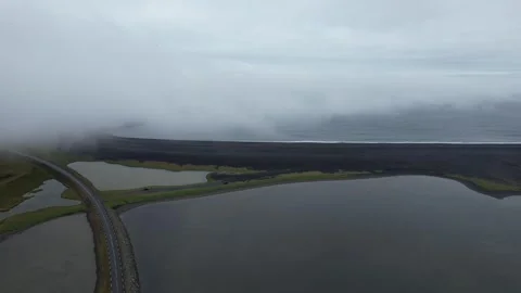 Aerial pan over lagoon and causeway road under low fog at Hvalnes, Iceland Stock Footage 346552137