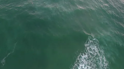 Aerial pan over of waves rolling through a group of surfers floating Stock Footage 157138644