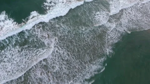 Aerial pan over waves slowly rolling onto the shore Stock Footage 157138643