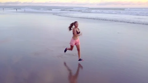 Aerial Pan Tracking Young Asian Sport Woman Running on Sunset Beach Stock Footage 88569957