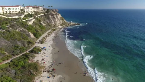 Aerial Pan of waves rolling along a beach coast Stock Footage 157234844