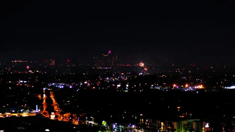 Aerial Panning Shot Of Fireworks Exploding Over Buildings In City, Drone Flying Stock Footage 243880716
